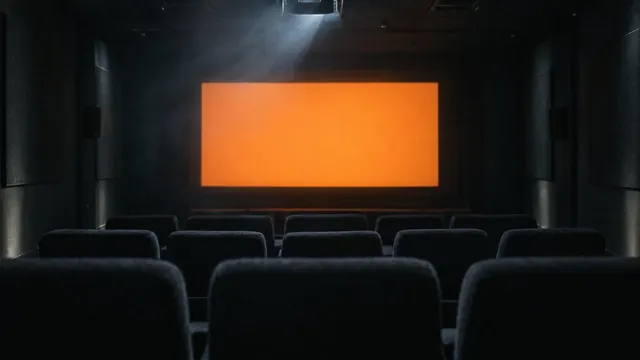 An empty screening room facing a glowing orange screen